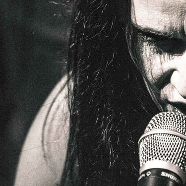 Chanteuse envoûtante sur scène, portrait en noir et blanc signé Thomas Bordas.