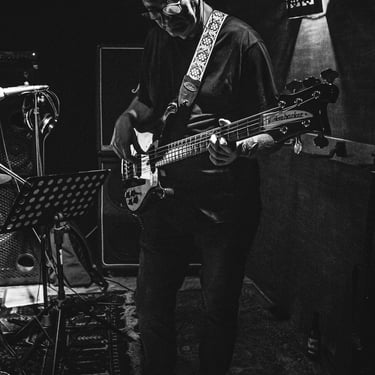 Portrait d’un bassiste en pleine performance, capté en noir et blanc par Thomas Bordas, vidéaste de concert.