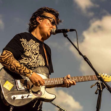 Émotion palpable d’un musicien lors d’un solo de guitare en plein jour, capturé par Thomas Bordas.