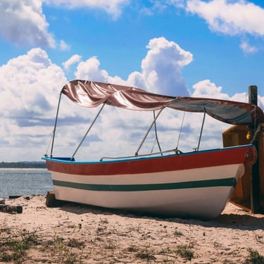 a boat on the beach with a sailboat in the water