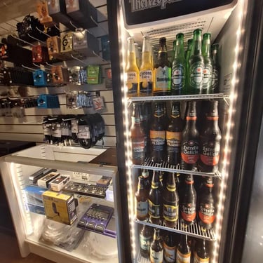 Geladeira com bebidas ao lado de acessórios musicais na loja do Studio Brothers em Porto Alegre