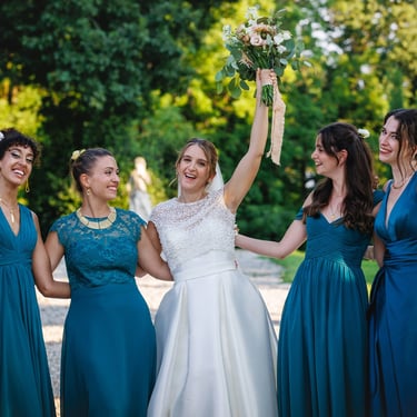 Fotoo di gruppo della sposa con le sue 4 damigelle d'onore, lei alza in aria il bouquet divertita