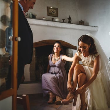 Durante i preparativi, la sposa indossa le scarpe osservata dagli occhi dolci del padre. Si trovano in una casa rurale