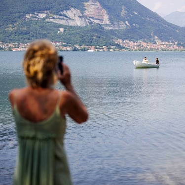 Una invitata riprende col telefonino l'arrivo della sposa su una barchetta bianca, sul lago di Como