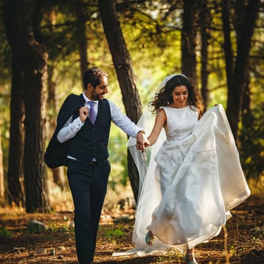 Due sposi si tengono per mano e corrono in un bosco in collina