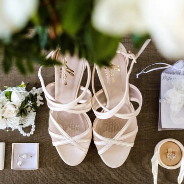 Uno still life degli oggetti della sposa, le scarpe, l'anello, gli orecchini e i fiori che decoreranno la sua acconciatura
