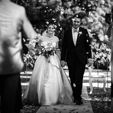 Gli sposi camminano tenendosi per mano nel corridoio di invitati che lanciano loro petali di rose dopo la cermonia di nozze