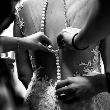 Le damigelle d'onore aiutano la futura sposa chiudendo i bottoni del retro dell'abito da sposa