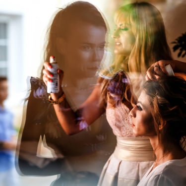 La parrucchiera sistema i capelli della futura sposa mentre una sua amica osserva dalla finestra