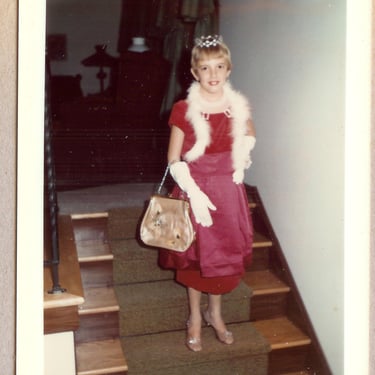 a young girl in a red dress and white fur stole