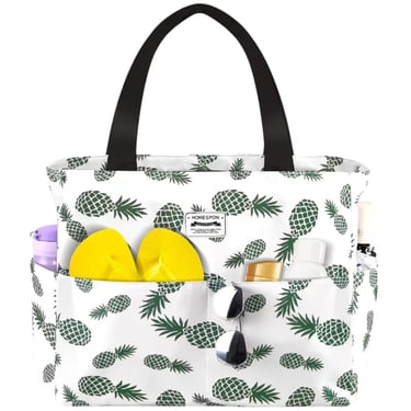 White pineapple print beach tote bag with yellow flip flops and sunglasses in outside pockets.