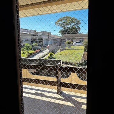 Porta da sacada vista por dentro com rede de proteção instalada.
