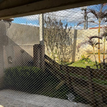 abertura de área coberta tipo garagem/varanda fechada com rede de proteção vertical; piso de cerâmica, jardim com gramado