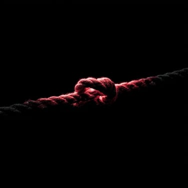 An intricately tied rope knot, textured and weathered, centered against a solid black backdrop