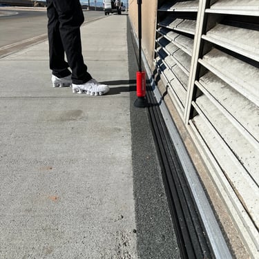 man using gas sniffer to check the rubber seal ouside of building