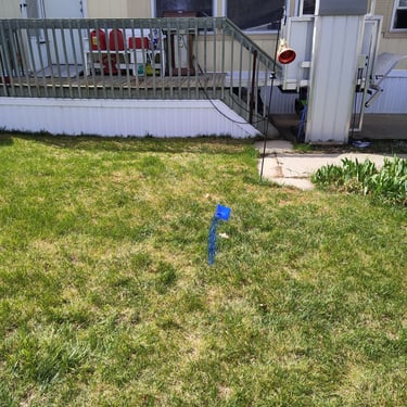 leak marked on the ground with blue paint in front of a mobile home