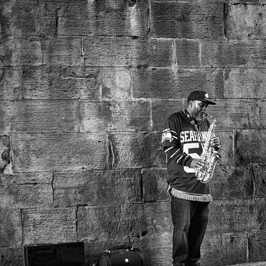 A sax player in a Seahawks jersey plays under the bridge on Calton Road, Edinburgh
