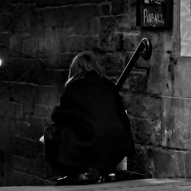 A woman, hunches down on the pavement by Craig's Close, Cockburn Street, Edinburgh