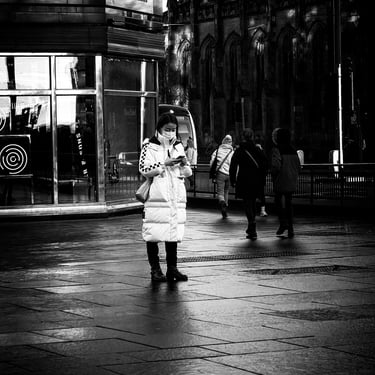 A woman tourist, wearing a face mask, stands at the West End, on her phone. Princes Street, Edinburgh