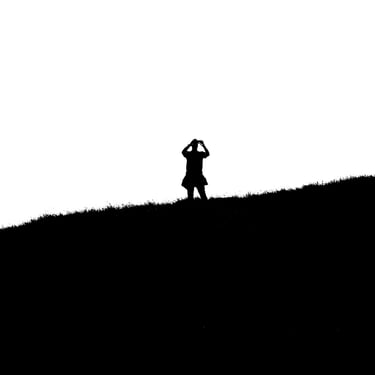 A figure stands taking a photo on Salisbury Crags, Edinburgh