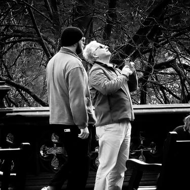 A man, holding his phone, at The Scott Monument into frame. East Princes Street Gardens, Edinburgh