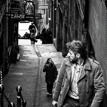 A man, his attention caught by something, glances over his shoulder. Fleshmarket Close, Edinburgh