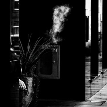 A man's hand, holding a cigarette, and a puff of smoke poke out of a doorway on Gardener's Crescent, Edinburgh
