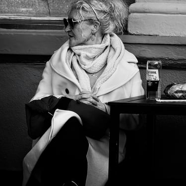 A woman sits having a beer on Waverley Bridge, Edinburgh