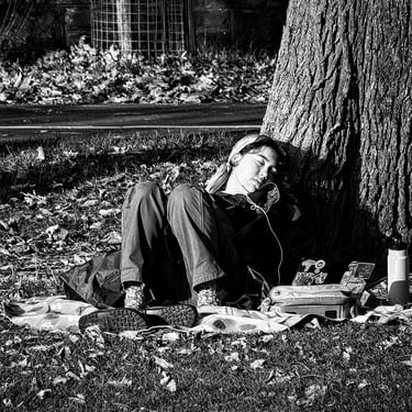 A young woman, propped up against a tree, has a wee snooze in the sun in The Meadows, Edinburgh