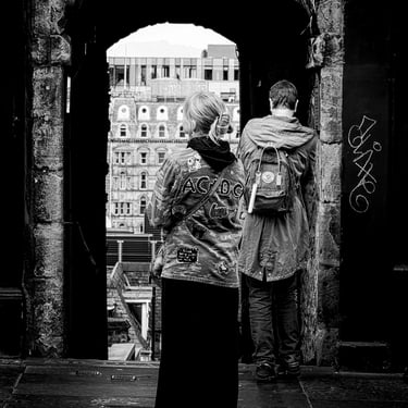 A woman wearing an AC/DC adorned jacket, stands at the entrance of Advocate's Close on The High Street