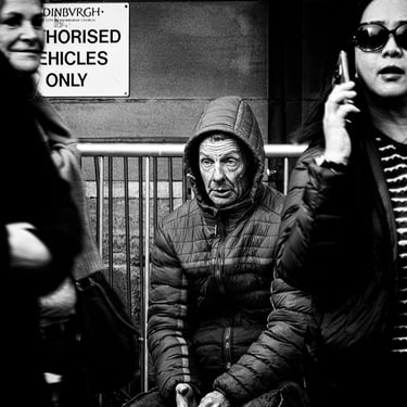 A man, either bored or confused, sits outside The City Chambers, The High Street, Edinburgh