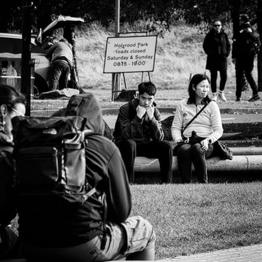 A bored looking young man and his mum sit on a stone bench near Holyrood Palace, Edinburgh