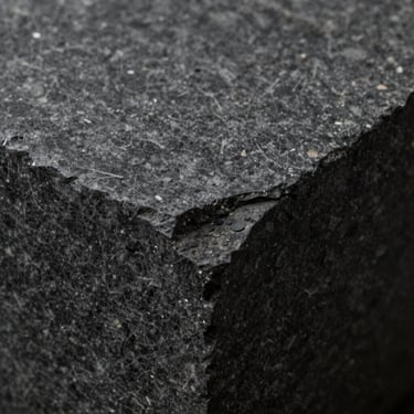 Macro texture of dark monolithic stone, soft diffused light.