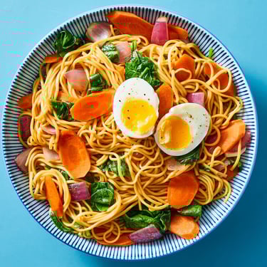 a bowl of noodles with eggs and vegetables