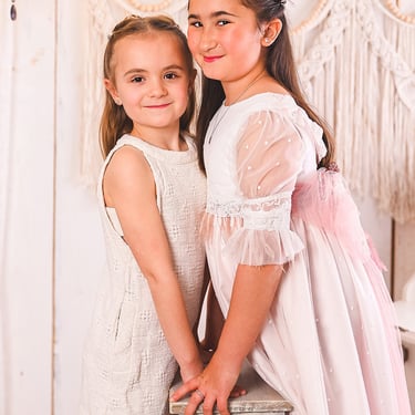 Reportaje de comunión de niña con hermana en estudio realizado por Amélie Art en Almendralejo