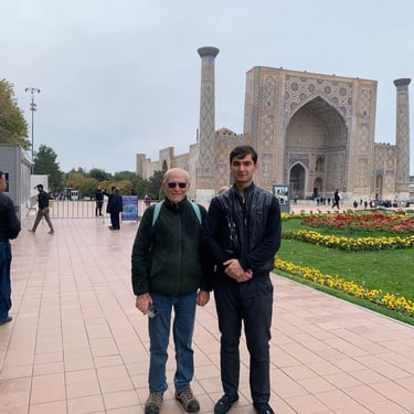 two men standing next to each other in front of Registan Samarkand