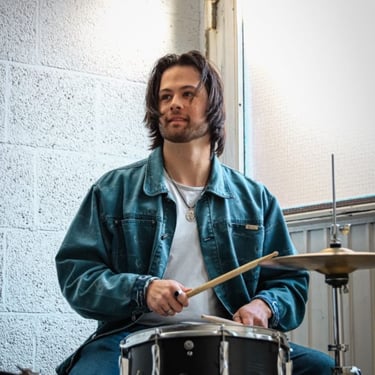 a man in a blue jacket playing drums