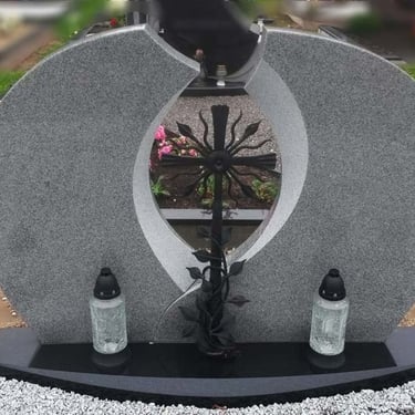 pilkos spalvos paminklas su metaliniu kryžiumi