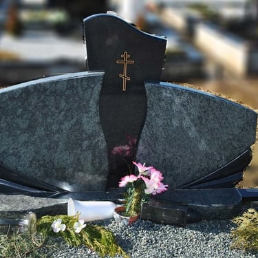 žalios spalvos paminklas su juodo akmens stulpeliu