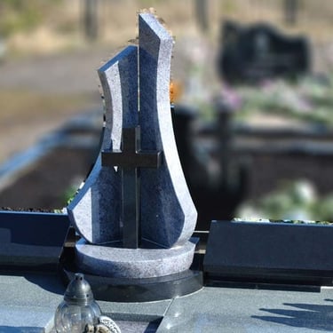 juodos ir pilkos spalvos paminklas su juodos spalvos kryžiumi