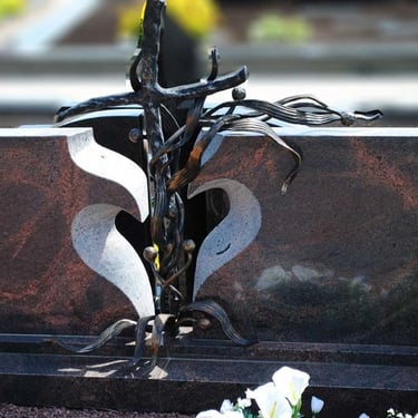 rudos spalvos Aurora paminklas su metaliniu kryžiumi per vidurį