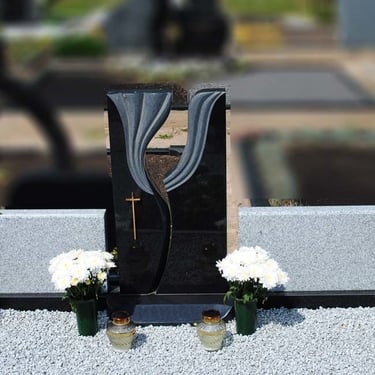 pilkos spalvos kelių dalių paminklas su juodo akemns stulpu