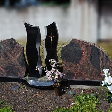 rudos spalvos kelių dalių paminklas su juodu stulpu