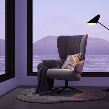 Cozy space with armchair, floor lamp, circular rug, large windows, and twilight view of lake and mountains.
