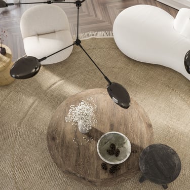 3D rendering of living room with round table, beige rug, curved sofa, chairs, lights, and vase.