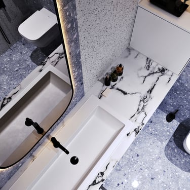 Modern bathroom with rectangular sink, black faucet, backlit mirror, marble countertop, speckled tiles, and stylish design.