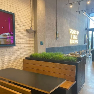 Interior of Pickl Uwalk in Saudi Arabia - Riyadh with white brick walls, concrete finishes, neon signage, and wood seating.