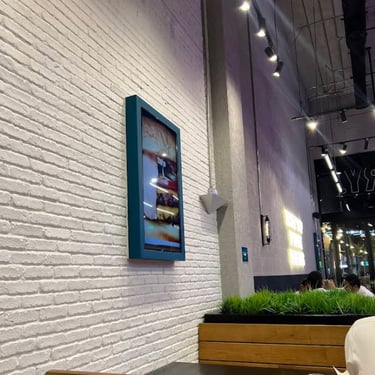 Interior of Pickl Uwalk in Saudi Arabia - Riyadh with white brick wall, food display screen, wood seating, and hanging lights