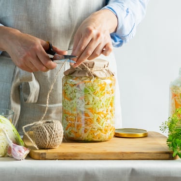 Person sealing a jar of homemade pickled cabbage and carrots for food preservation and long-term emergency food storage