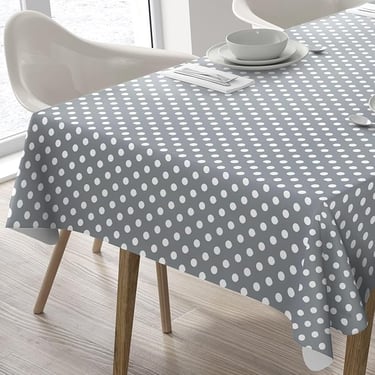 Modern grey and white polka dot tablecloth draped over a dining table with place settings.